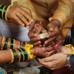 Close-up of a Hindu wedding ceremony showing hands adorned with henna and traditional jewelry.